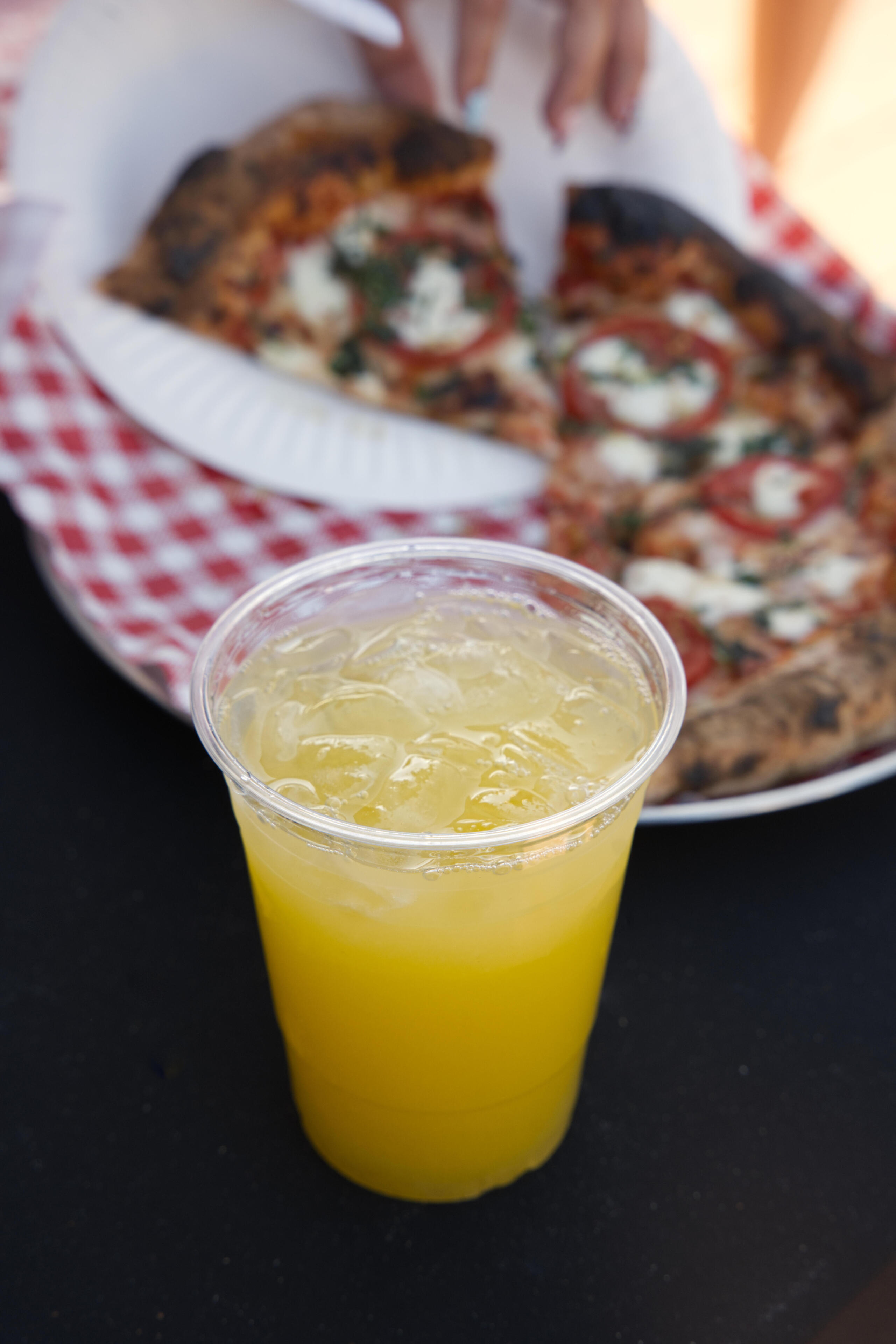 Menu cup with mango agua Fresca with pizza in the background
