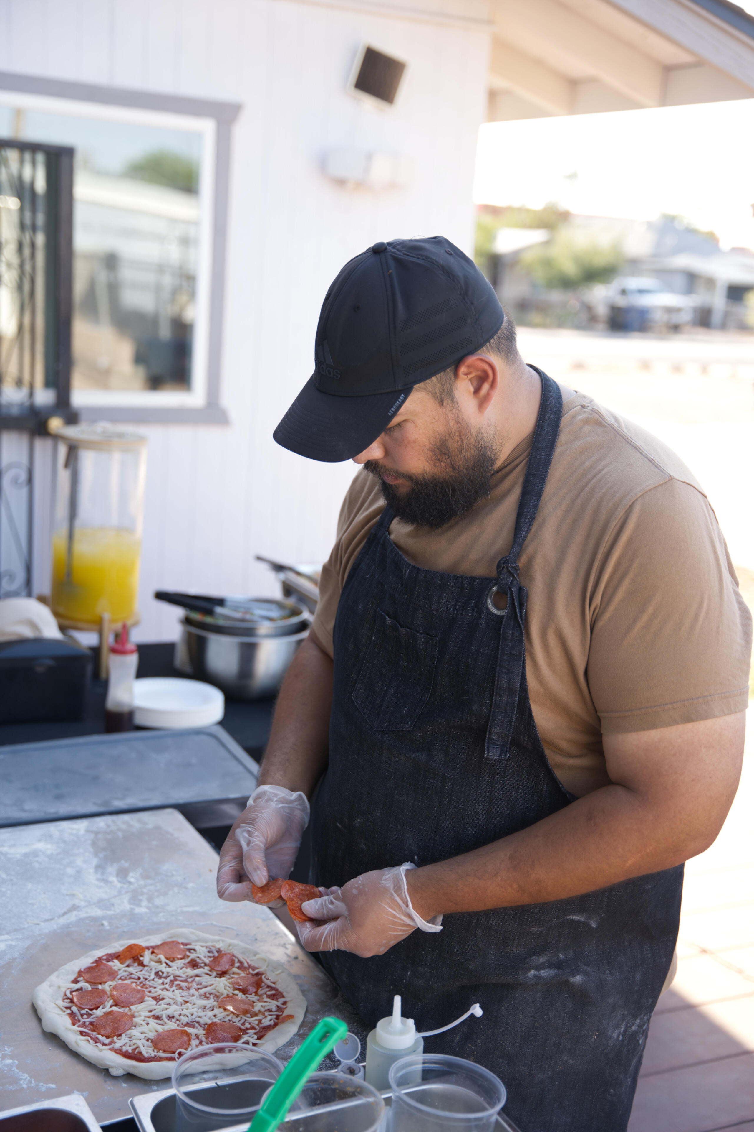 Menu picture of a person topping a pizza